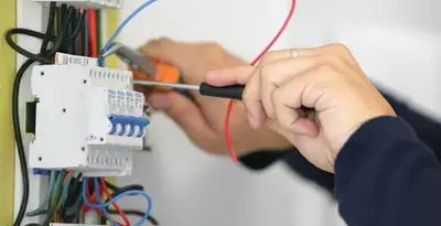 Electrician installing and adjusting circuit breakers in an electrical panel in Bloomington, IN